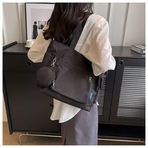 Model carrying a large black canvas tote bag with a small coin purse, back view.