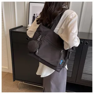 Back view of a minimalist black canvas tote bag for women with a matching small pouch