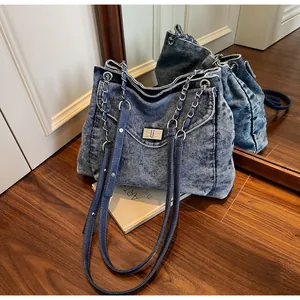 Vintage blue acid-wash denim large shoulder bag with silver chain straps and turn-lock.