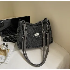 Detailed view of the vintage black washed denim shoulder bag with silver chain straps.