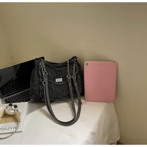 Large capacity vintage denim shoulder bag shown next to laptop for size reference