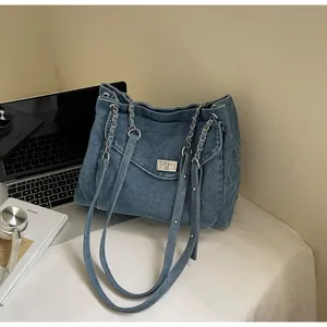 Close-up detail of retro large capacity blue denim tote bag with silver chain straps