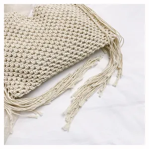 Detailaufnahme einer handgefertigten Makramee-Tasche in Cremeweiß mit langen Fransenquasten