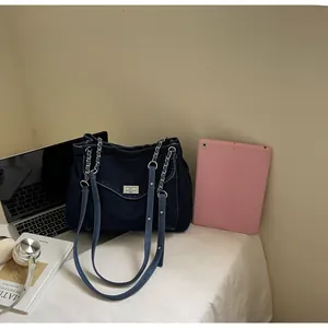 Vintage dark blue denim shoulder bag with chain straps and metal turn-lock closure