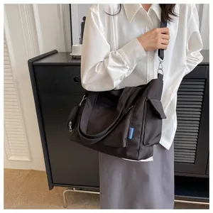 Minimalist black canvas tote bag with extra pouch shown on model for daily commuting