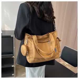 Close-up detail of a large mustard yellow canvas tote bag with side pouch worn by a fashion model
