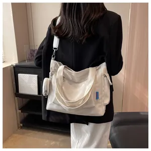 Detailed view of high capacity white canvas tote bag worn on shoulder by model in casual setting