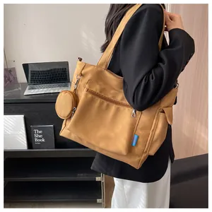 Large brown canvas tote bag with side pockets and a small round coin purse charm