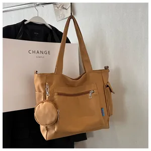 Close-up view of a khaki canvas tote bag featuring front zip pocket and round pouch.