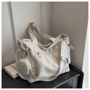 Detail of a cream canvas tote bag with multi-pockets and a small round pouch accessory