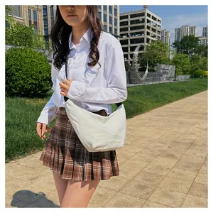 Modelo asiática con un gran bolso bandolera blanco crema en forma de media luna
