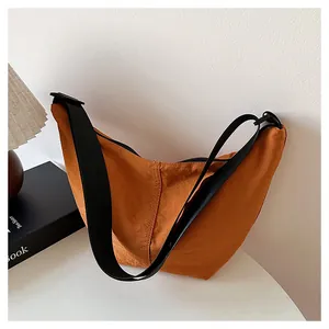 Detalle de un bolso bandolera minimalista en forma de media luna color naranja