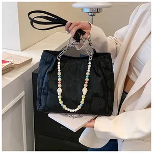 Detailed view of black jacquard tote bag featuring a decorative colorful beaded chain