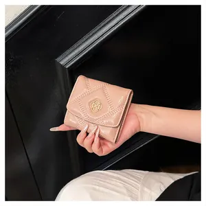 Close-up of a pink quilted patent leather short wallet with an elegant gold buckle