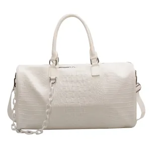 Detail of a white crocodile-textured travel bag with stylish thick white chain strap.