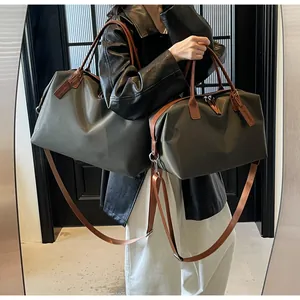 Comparison of two sizes of large dark gray nylon travel duffel bags with brown straps