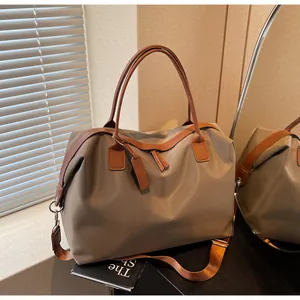Khaki large travel duffle bag with brown leather handles in a cozy indoor setting