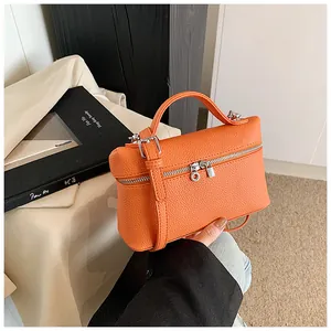 Detalle de un bolso de mano naranja brillante de cuero PU texturizado con cremallera plateada