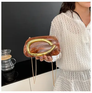 Detailed view of a marble-patterned clutch with a bold gold-tone circular handle