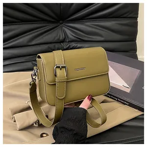 Macro view of an olive green vintage small square bag with metal buckle on a beige coat