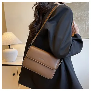 Side detail of a brown retro textured square crossbody bag worn over a black blazer.