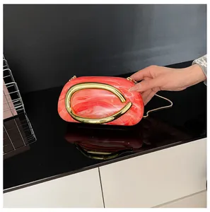 Elegant red marble texture evening clutch bag featuring a vintage gold circular handle