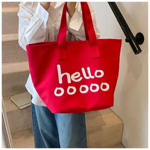 Vista detallada del bolso tote grande de lona roja con estampado 'hello' blanco