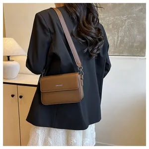 Rear view of a stylish brown minimalist crossbody bag worn with a black blazer