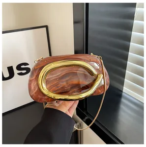 Close-up detail of a brown marbled evening clutch bag featuring a gold C-shaped handle