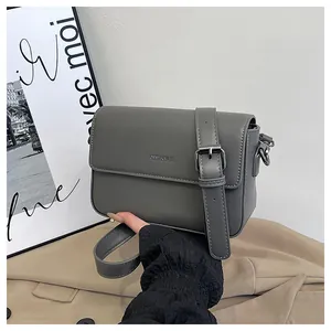 Close-up detail of a minimalist grey faux leather square crossbody bag held in hand