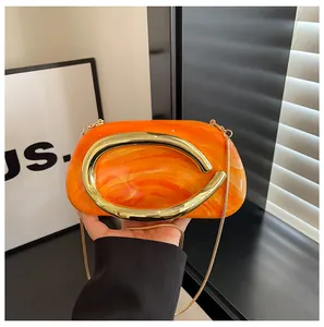 Detail of orange marble evening clutch with vintage gold C-shaped metal handle