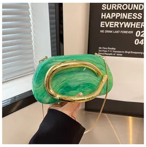 Close-up of green marbled mini clutch with chunky gold C-handle and chain