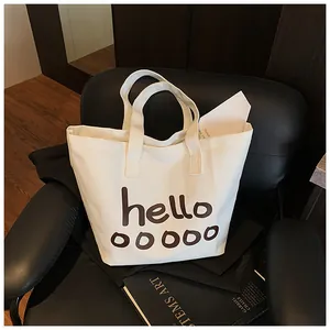 Vista detallada de un bolso de lona blanca con estampado de letras hello marrones