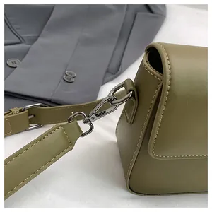 Close-up of olive green faux leather crossbody bag detailing hardware and stitching.