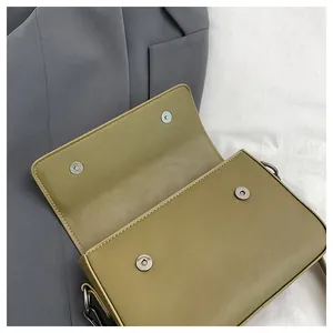 Detail view of the magnetic snap closure on an olive green minimalist square bag