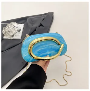 Detailed view of a blue marble clutch bag featuring a large gold C-shaped handle.