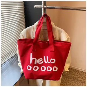 Vista detallada de un gran bolso tote de lona roja con estampado de letras hello