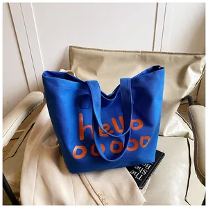 Bolso tote de lona azul con estampado hello naranja en un entorno de estilo de vida urbano