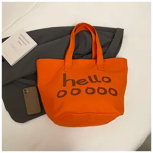 Vista detallada del bolso tote de lona naranja con un elegante estampado hello en marrón.