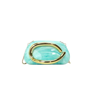 Macro view of cyan marble resin evening clutch bag featuring a gold handle.