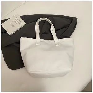 Detalle de un bolso de lona blanco minimalista sobre una americana gris