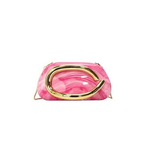Close-up of pink marble evening clutch with a stylish golden metal handle detail