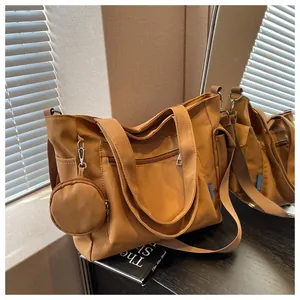 Detail view of a khaki canvas tote bag with a small matching coin purse accessory.