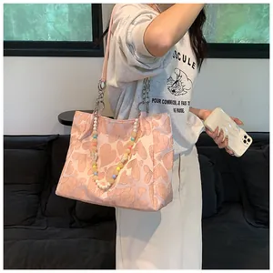 Stylish model wearing a pink heart-patterned tote bag with colorful beaded charm.