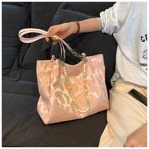 Detailed view of the pink heart pattern tote bag featuring a colorful beaded chain.