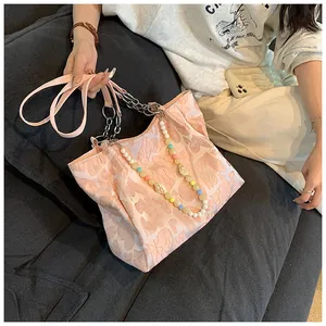 Lifestyle detail of a pink heart pattern tote bag with colorful beaded strap.