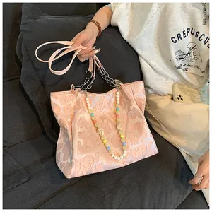 Model holding a pink heart-patterned tote bag with a colorful bead chain accessory