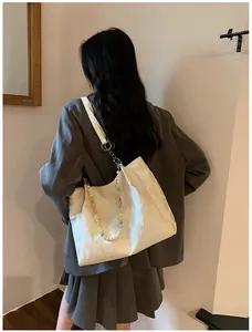 Stylish white embossed tote bag featuring colorful beaded strap on model shoulder view
