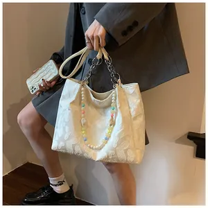 Detail of a white tote bag featuring colorful bead straps and heart-embossed fabric.