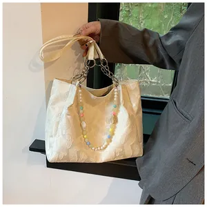 Close-up of white jacquard tote bag featuring colorful beaded handle and chain